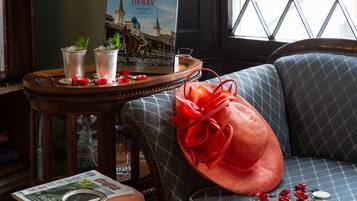Un libro con el título "The Kentucky Derby", un sombrero rojo y un collar decorativo con flores rojas.
