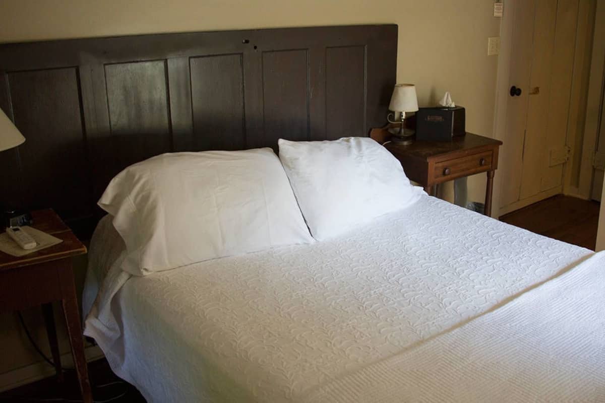 A neatly made bed with white linens in a hotel room.