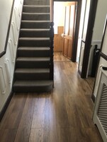 Una escalera de madera con un rellano alfombrado que lleva a una habitación con suelo de madera.