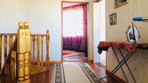 Eine Treppe mit hölzernen Geländern, einem gemusterten Teppich und einem Bügelbrett mit Bügeleisen.