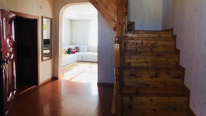 Eine Holztreppe führt zu einem Wohnbereich mit einem weißen Sofa und einem Teppich.