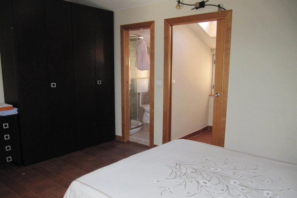 A bedroom with a bed, a wardrobe, and a bathroom visible through an open door.