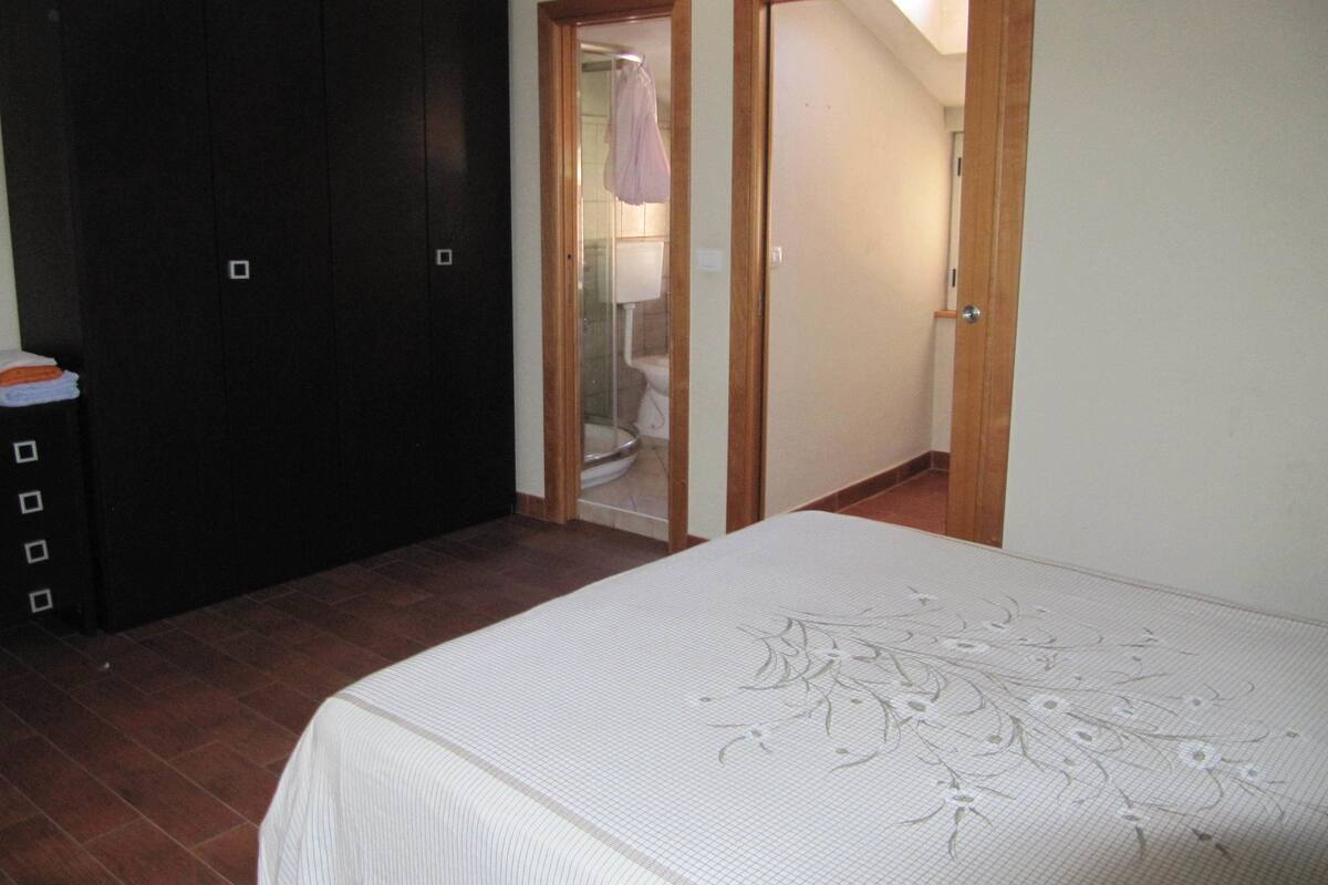 A bedroom with a bed, a wardrobe, and two doors leading to other rooms.