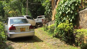 Un chemin pavé avec une voiture garée et un bâtiment doté d’un balcon.