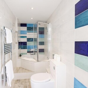 A modern bathroom with a glass shower enclosure, a white toilet, and a bathtub. - THE Cumberland (Bournemouth)