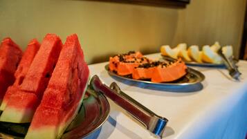Une table de buffet avec des tranches de pastèque et d’autres fruits.
