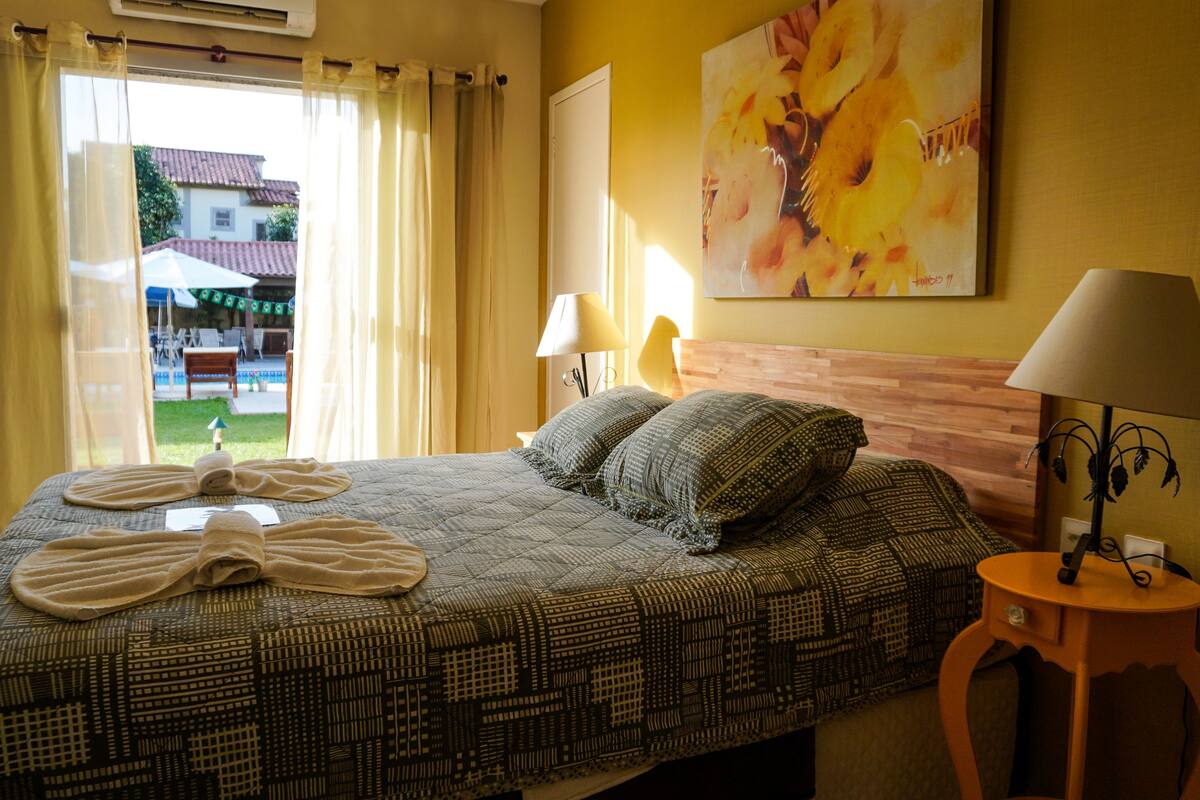 Une chambre d’hôtel avec un lit, une table de chevet, une lampe et un tableau au mur.