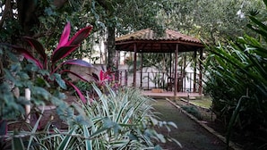 A gazebo surrounded by lush greenery and a stone wall. - Pousada das Garças de Saquarema (Saquarema)