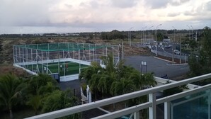 A view of a sports field with a rainbow, surrounded by a parking area and palm trees. - Luxor Residence Guest House (Belle Mare)