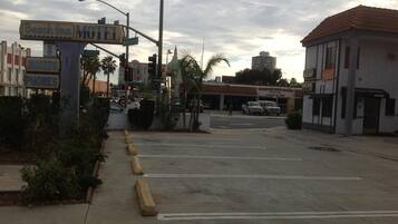 Vista de la calle con un letrero de motel, un concesionario de coches europeos y un edificio con un cartel de oficinas.