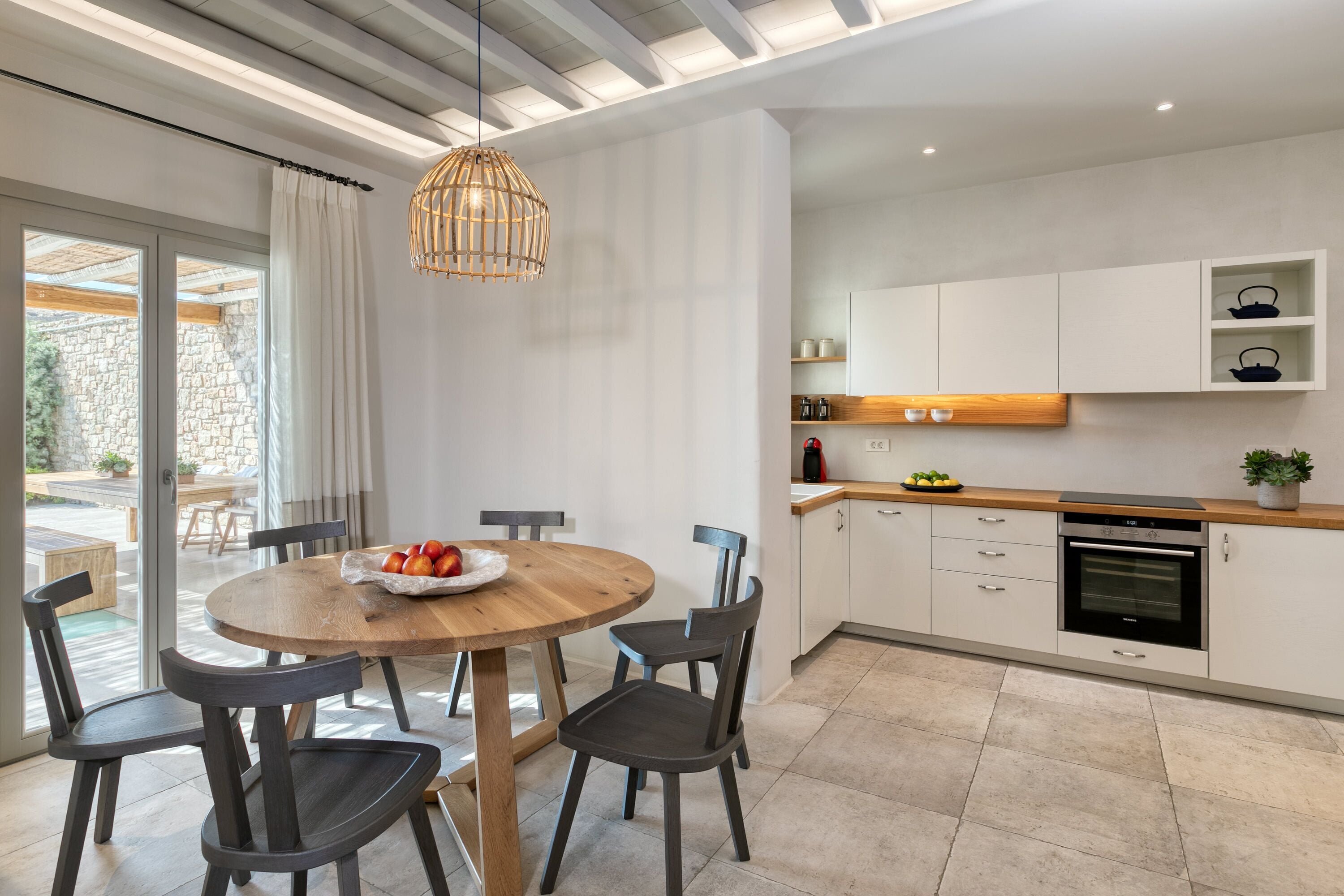 Una cocina moderna con armarios blancos, encimera de madera y horno empotrado.