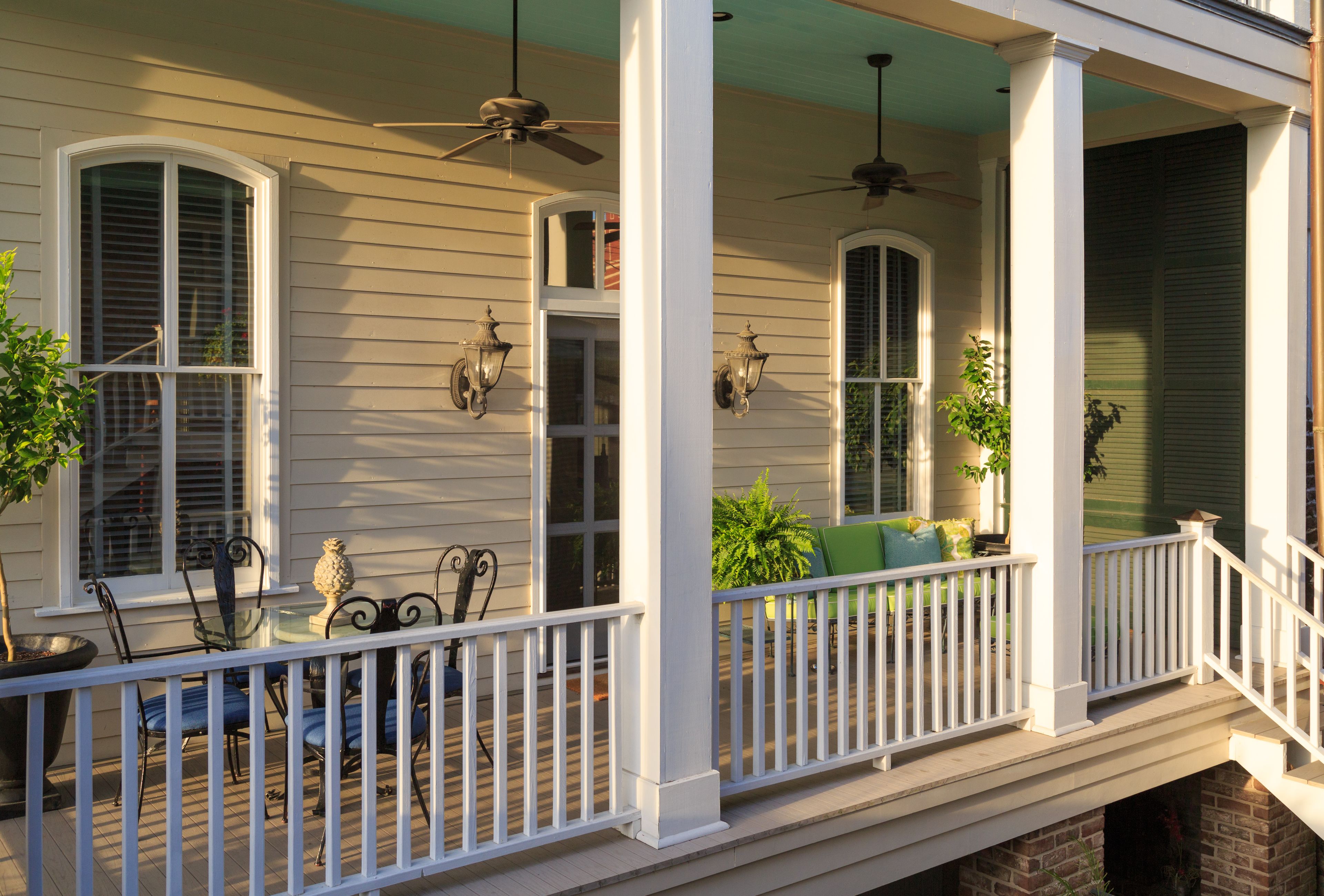 A covered porch with white railings, two ceiling fans, and a brick fireplace.