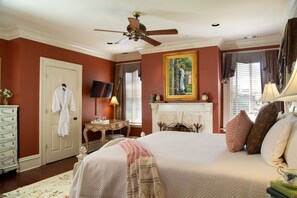 A bedroom with a large bed, a ceiling fan, a fireplace, and a television on a dresser. - The Inn on West Liberty (Savannah)