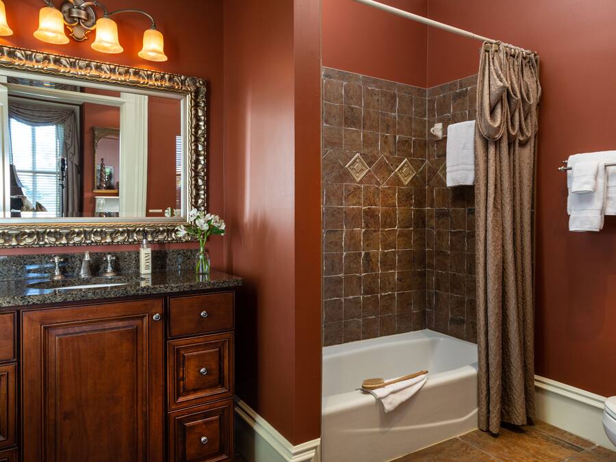 A bathroom with a vanity, a bathtub, and a shower curtain.