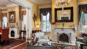 A traditional living room with a fireplace, a chandelier, and classic furniture. - The Inn on West Liberty (Savannah)