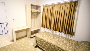 Un dormitorio pequeño y ordenado con una cama individual, una mesita de noche, un armario y una ventana con cortinas.