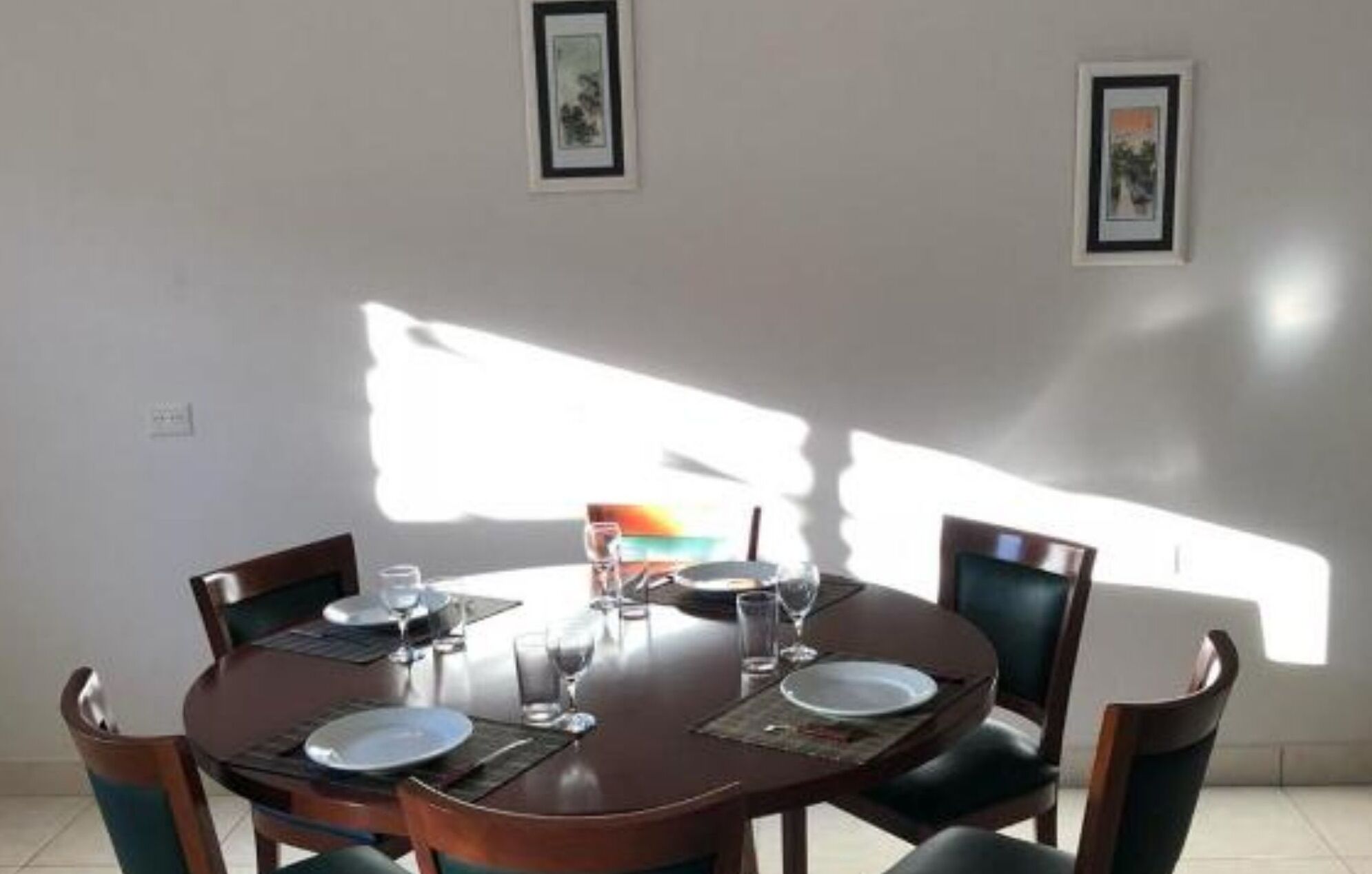 A dining area with a round table, chairs, and framed pictures on the walls.
