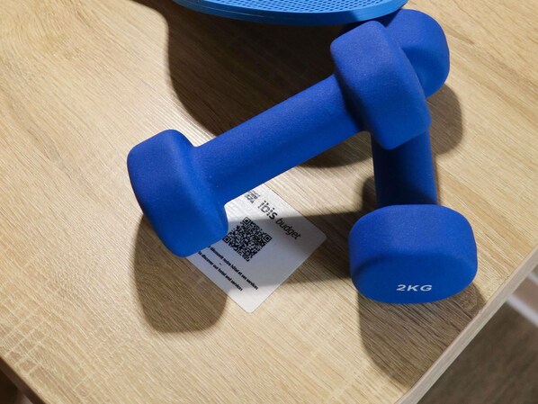 Un par de mancuernas azules con etiqueta de peso y un código QR sobre una superficie de madera.