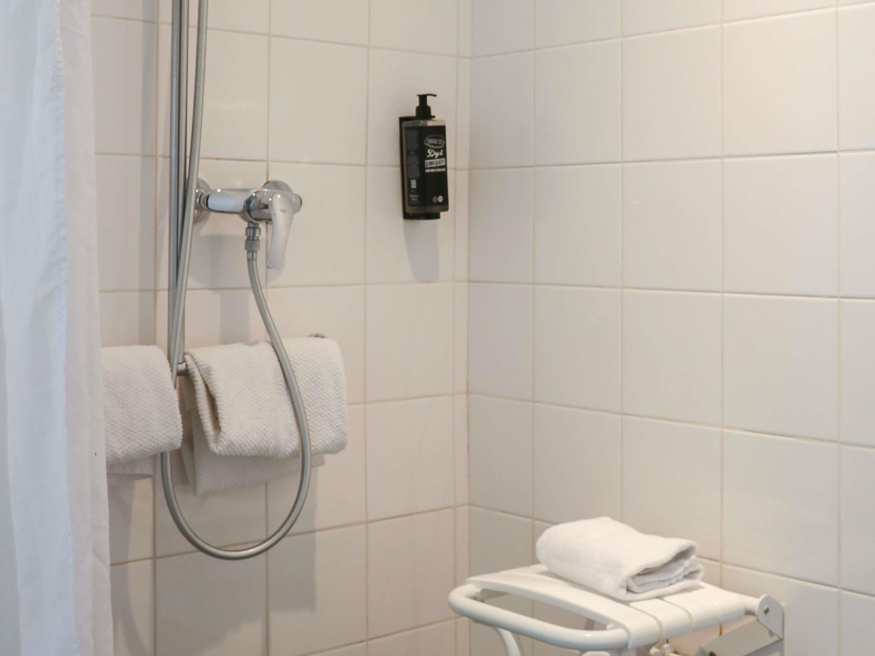 A bathroom with a shower, a toilet, and a towel rack.