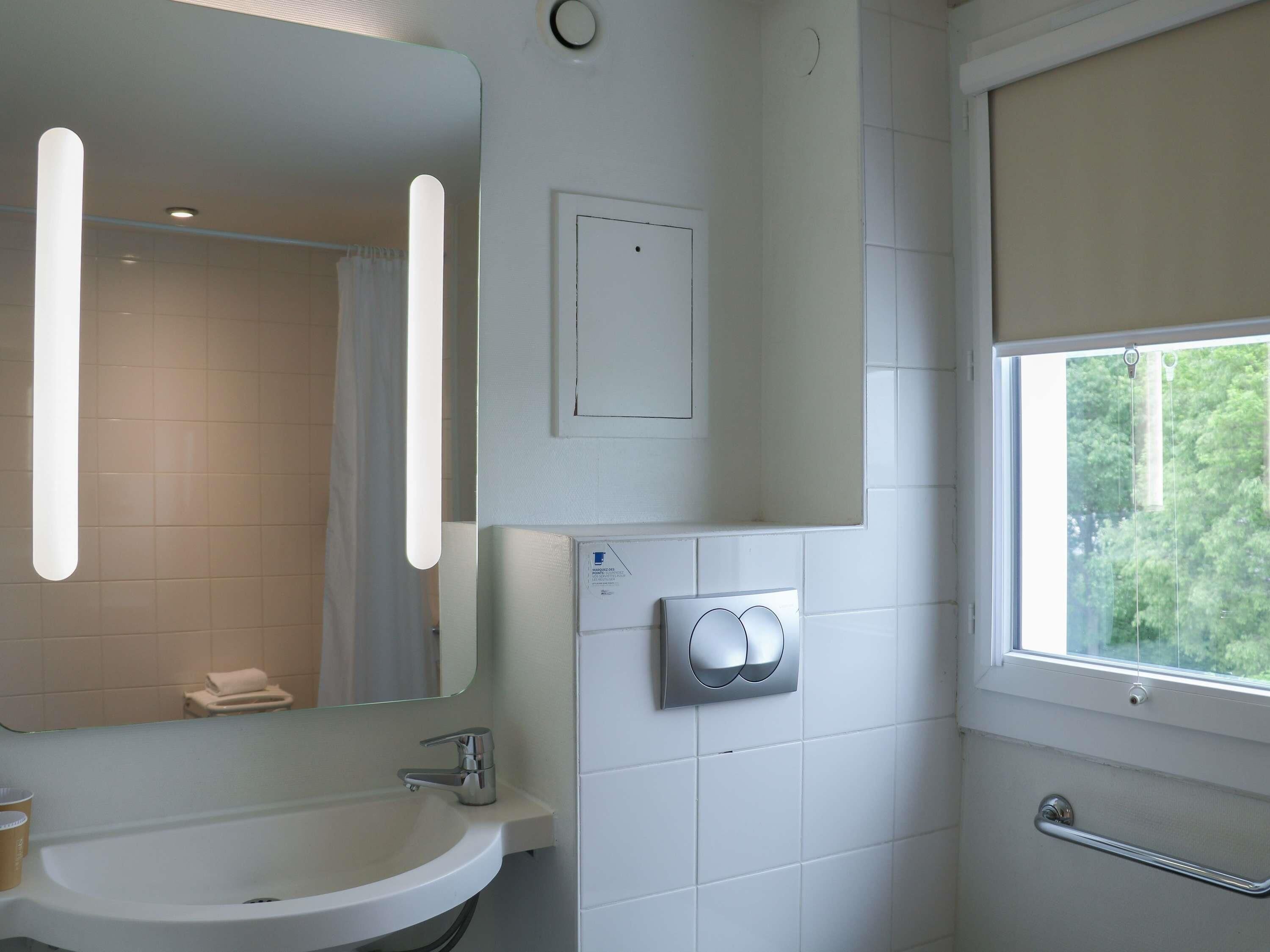 Ein Badezimmer mit Waschbecken, Spiegel und Fenster.