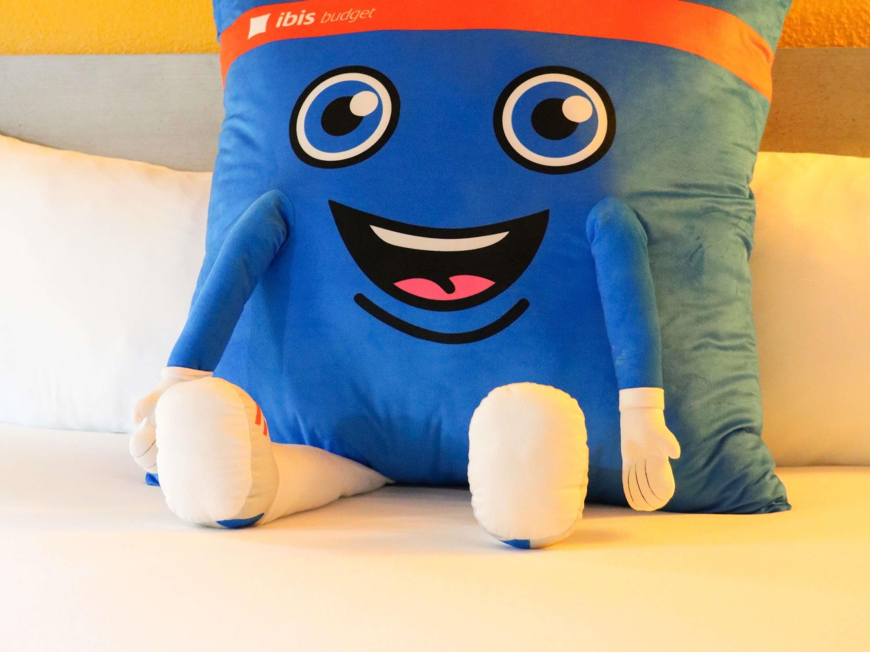 Een zacht knuffeldiertje met een lachend gezicht en grote ogen, op een wit oppervlak.