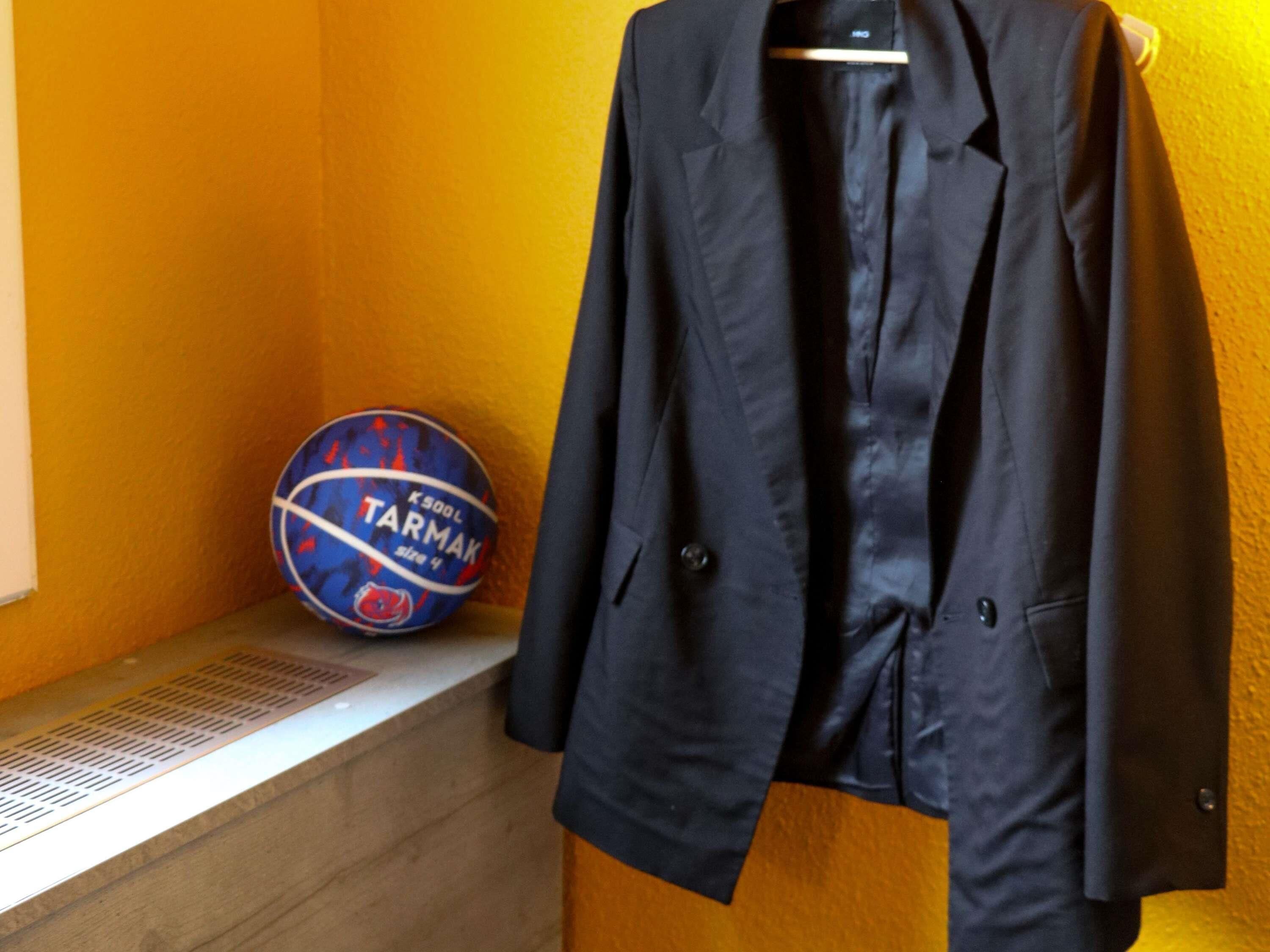 A basketball, a black jacket, and a wall with a vent.