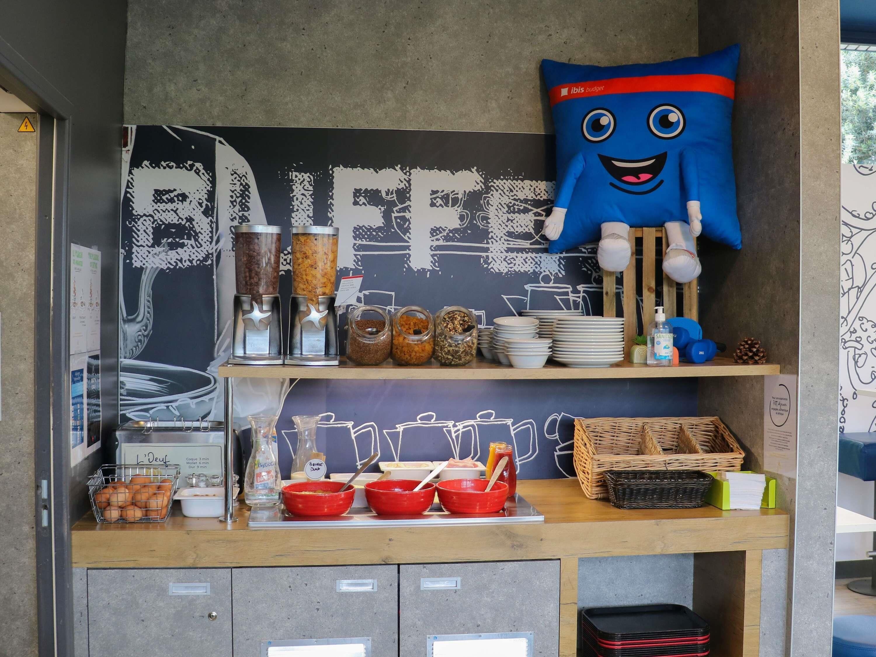 Montaje de bufé con recipientes de comida, un almohadón azul grande y varios utensilios de cocina.