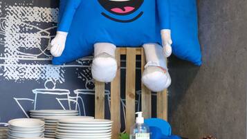 Una stanza con un peluche azzurro, ciotole bianche impilate, una bottiglia di disinfettante, manubri azzurri e un pigna.