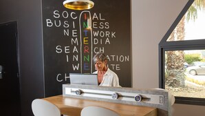 Un mostrador de recepción con una computadora portátil, una mujer de pie detrás y una pared con palabras como 'SOCIAL BUSINESS' e 'INTERNEWS'.