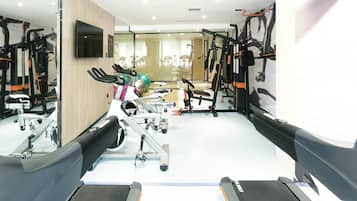 Un gimnasio con equipo de ejercicio diverso, incluyendo cintas de correr, bicicletas estáticas y máquinas de pesas.