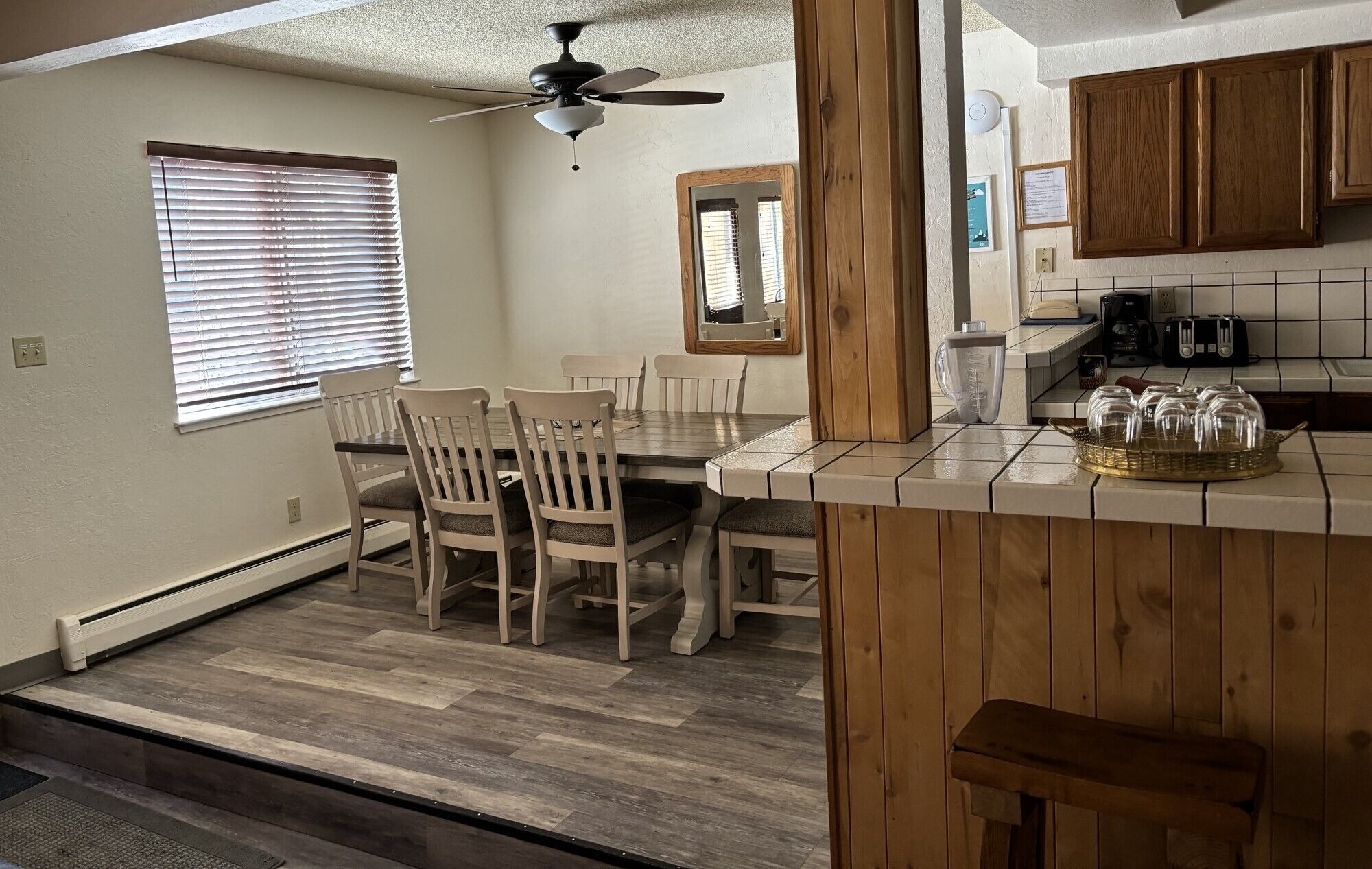 A compact kitchen with a dining area, wooden cabinets, and a ceiling fan.