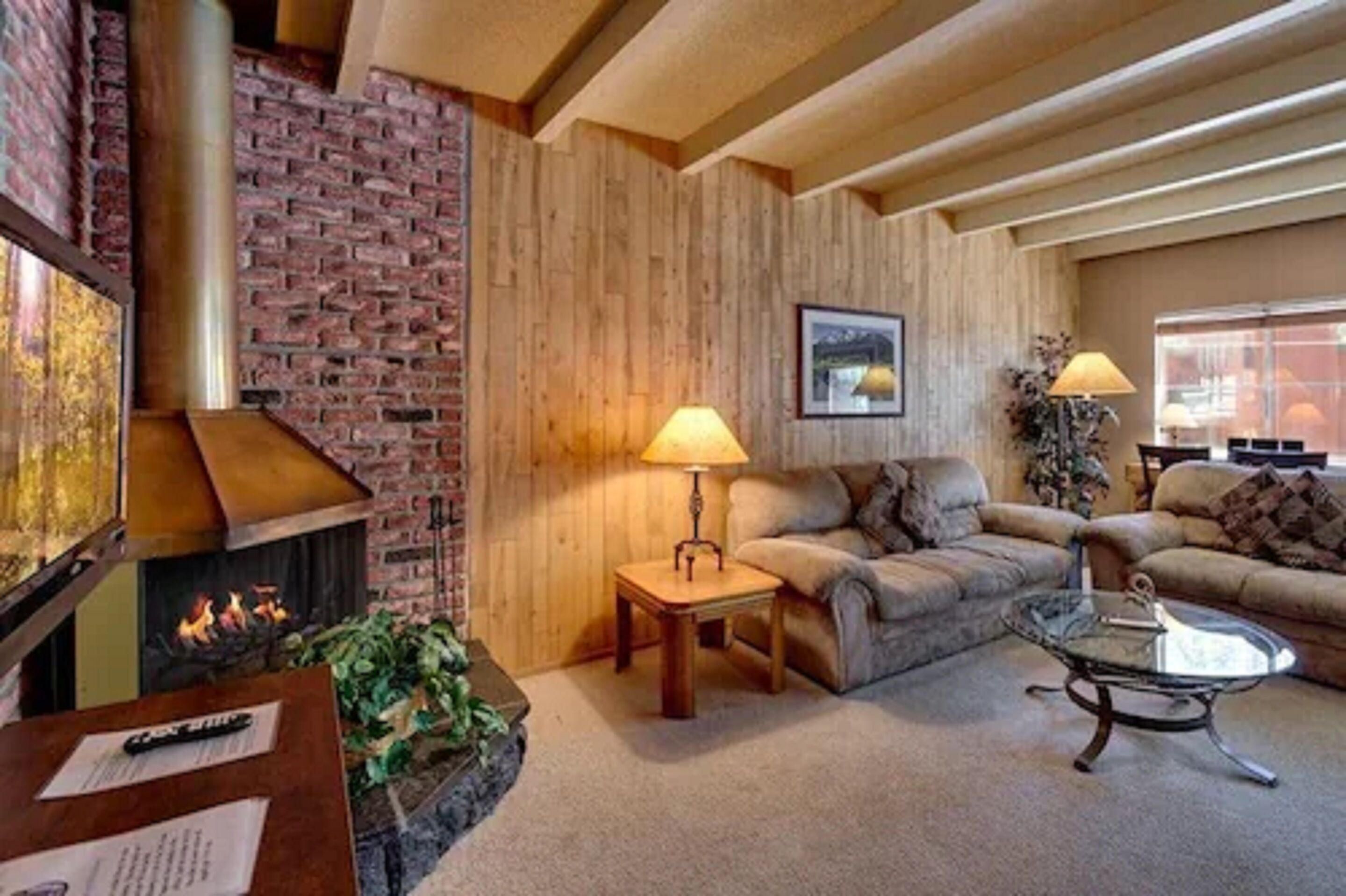 A cozy living room with a fireplace, a sofa, a coffee table, and a lamp.