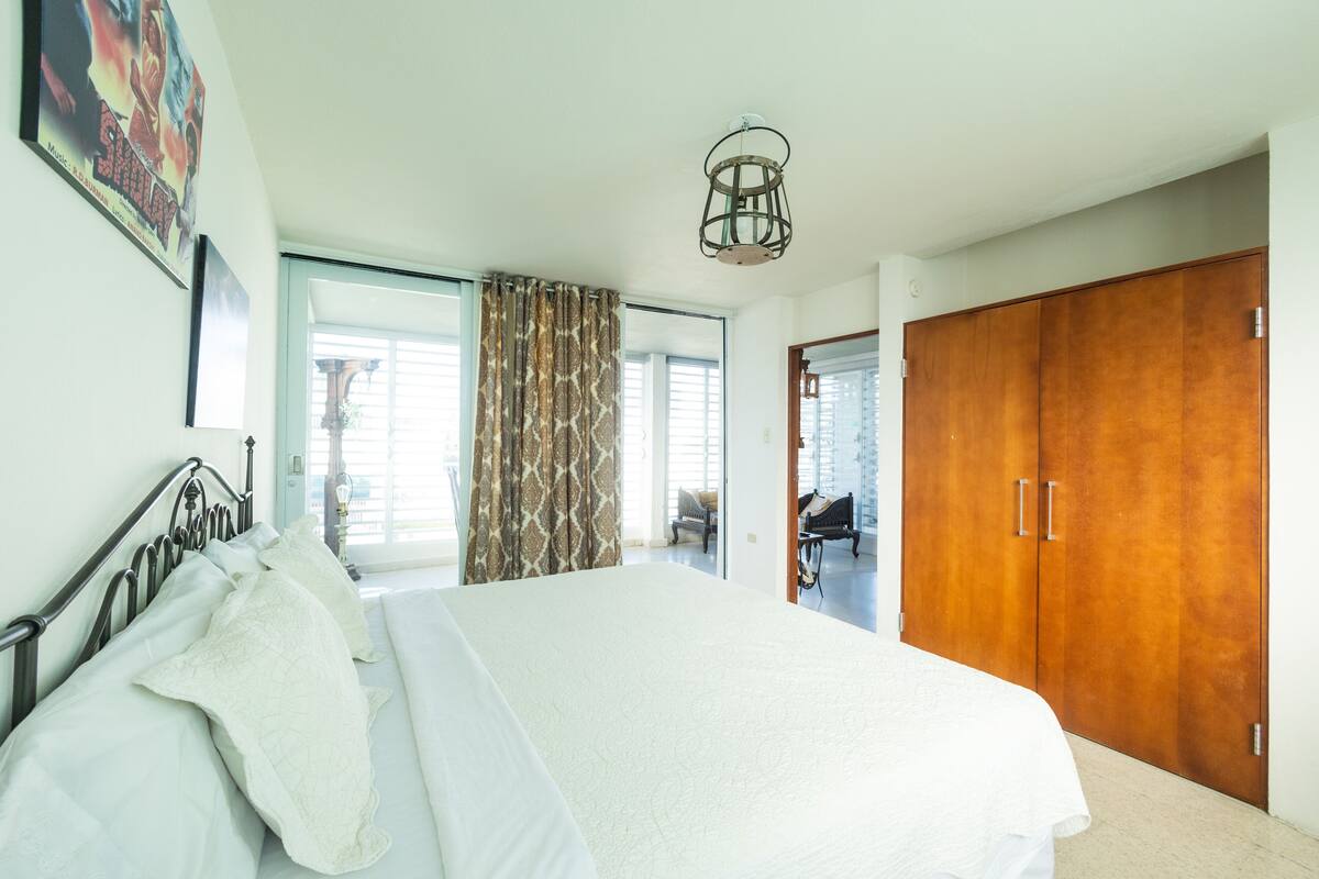 A bedroom with a large bed, a wardrobe, and a window with curtains.