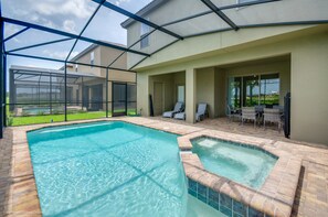 A swimming pool with a glass enclosure, a patio area with chairs and tables, and a view of a residential area. - Solterra - 5569 Misty Oak Circle (Davenport)