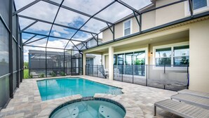 Ein Pool mit Whirlpool und Liegestühlen, der von einer Glasdachkonstruktion überdacht und von Steinfliesen umgeben ist.
