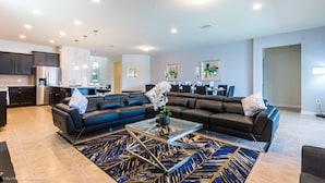 A modern living room with a sectional sofa, a glass coffee table, and a patterned rug. - Windsor at Westside - 1639 Lima Avenue (Kissimmee)