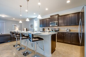 A modern kitchen with dark cabinets, stainless steel appliances, and a central island with bar stools.