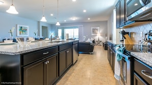 A modern kitchen with granite countertops, stainless steel appliances, and pendant lighting. - Windsor at Westside - 1639 Lima Avenue (Kissimmee)