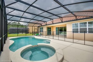A covered outdoor swimming pool area with a hot tub, a patio, and a view of a house with a tiled roof. - Solterra - 6136 Broad Oak Drive (Davenport)