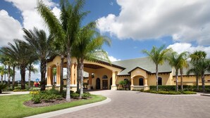 A hotel with a central courtyard, palm trees, and a paved walkway.