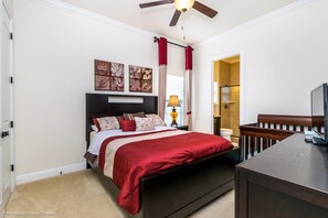 Une chambre à coucher comprenant un lit, une table de chevet, un bureau et un ventilateur de plafond.