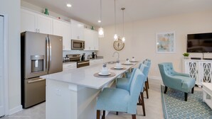 A modern kitchen with white cabinets, stainless steel appliances, and a central island with seating. - Storey Lake - 4832 Romeo Circle (Kissimmee)