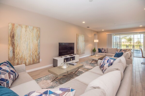A modern living room with a large sofa, a flat-screen TV, and a coffee table.