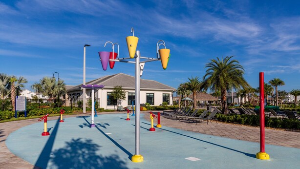 A playground with colorful equipment, a building with a white facade, and palm trees in the background. - Storey Lake - 4777 Kings Castle Circle (Kissimmee)