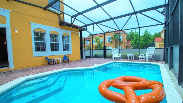 An indoor swimming pool with a clear glass roof, surrounded by yellow walls and white chairs. - Terra Verde Resort - 101 Pompano Beach Dr (Kissimmee)