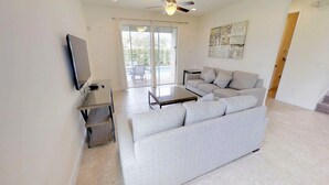 A living room with a sofa, a coffee table, a TV, and a ceiling fan.