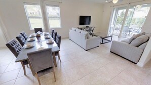 A modern living room with a dining area, a sofa, and a TV.
