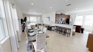 Una cocina moderna con una isla central, taburetes de bar y un comedor con una mesa redonda y sillas.