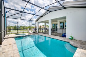 Une piscine dotée d’une structure en verre, d’un espace extérieur aménagé et offrant une vue sur les environs.
