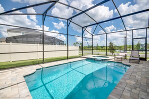 Une piscine dotée d’un espace couvert, une terrasse avec des chaises et une vue sur une maison et des arbres.